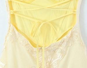 Détail d'une robe en tulle jaune clair avec lacets croisés et broderies florales 3D