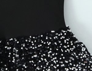 Détail d'une robe noire montrant la couture entre le tricot et la jupe à paillettes argent