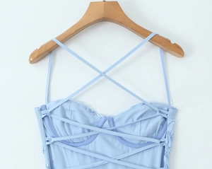 Detail of light blue mesh dress featuring cross-strap design and 3D floral accents
