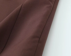 Detail of dark brown twill fabric showing fine texture and professional side seam stitching