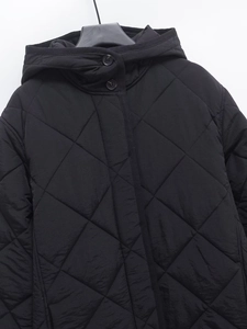 Detail of black quilted hooded coat with diamond pattern stitching and button closure