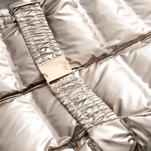 Detail of metallic ski jacket with elastic waist belt and gold-toned metal buckle
