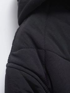 Close-up of quilted stitching and fabric texture on a black hooded winter coat