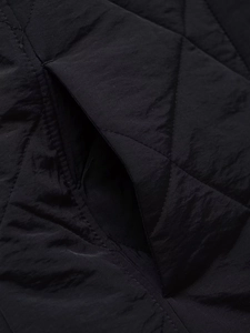 Close-up of diamond quilted fabric with side pocket detail on black winter coat