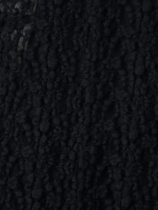 Macro view of textured black floral lace fabric with intricate 3D patterns and sheer details