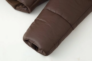 Macro detail of the dark brown quilted sleeve cuff on a thick winter hooded cotton coat