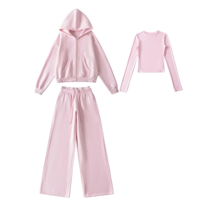 Detailed flat lay of pink three-piece athletic set with hoodie, crop top, and wide pants