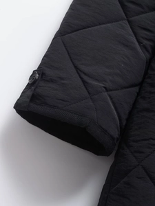 Detail of quilted diamond pattern fabric with windproof ribbed cuffs and button closure