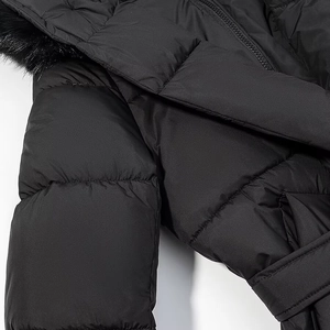 Détail d'un manteau matelassé noir avec capuche en fourrure, zip et ceinture à la taille