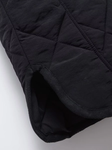 Macro view of black quilted winter coat detail showing ripstop fabric and diamond stitching