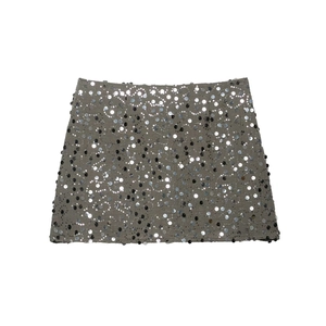 Detail showing high-waisted sequined mini skirt with intricate metallic silver and black sequins