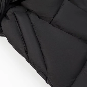 Détail d'un manteau noir à capuche avec surpiqûres en losanges et poche latérale