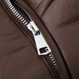Macro view of dark brown quilted winter coat featuring a high-quality silver metal zipper