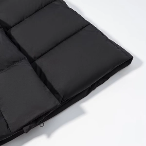 Détail macro du tissu matelassé noir de la doudoune avec finition de la fermeture éclair