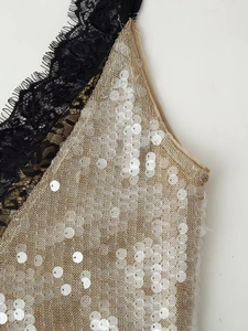 Close-up of gold sequin fabric with delicate black eyelash lace and knit texture