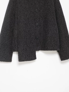 Macro shot of charcoal grey boucle fabric texture with three black buttons and slit hem