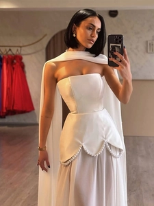 Detail of white strapless dress featuring elegant pearl embellishments and matching shawl