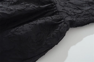 Primer plano de tela jacquard negra que muestra textura grabada y detalles de costura
