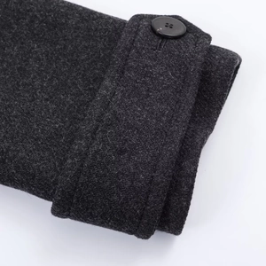 Macro shot of dark grey wool coat cuff featuring adjustable strap and black button details