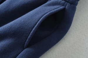 Detailed view of the side pocket and thick knitted fabric on navy sweatpants