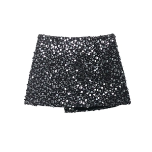 Vue détaillée de paillettes argentées en spirale sur tissu noir avec un ourlet asymétrique