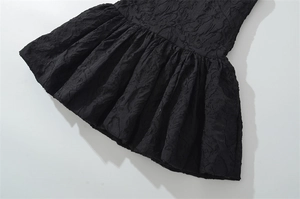Vista detallada de la tela de jacquard negro texturizado y el dobladillo plisado