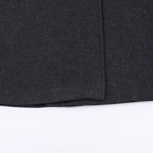 Close-up of the dark grey wool blend fabric and neat hemline stitching on the overcoat