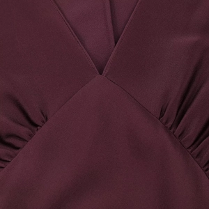 Detail of V-neckline with gathered pleats on burgundy satin texture long sleeve dress