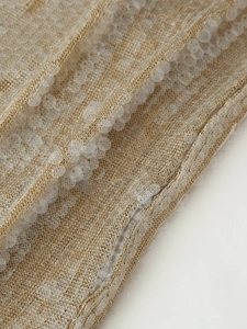 Detailed close-up of glittering sequins on delicate mesh lace fabric for a chic dress