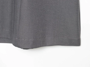 Detailed close-up of dark grey twill fabric texture and neat stitching on dress hemline