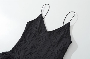 Detalle del escote en V y textura de jacquard 3D en el vestido negro de espalda aire