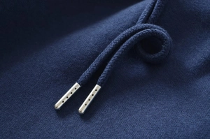 Macro shot of dark blue knit fabric with a silver metal-tipped drawstring detail