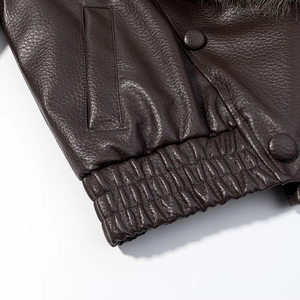 Detailed view of dark brown leather jacket with elastic hem and fur collar accents
