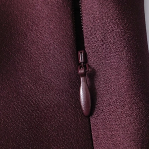 Macro shot of invisible zipper detail on dark red satin long sleeve dress