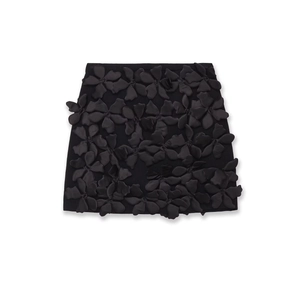 Détail d'une mini-jupe noire avec appliques florales 3D complexes et textures variées