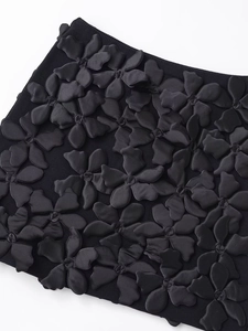 Détail d'appliqués de fleurs 3D en satin sur une mini-robe en maille noire chic