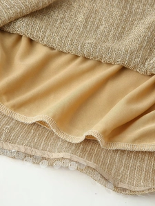 Macro shot of champagne gold textured lace with sparkling sequins and fine stitching details