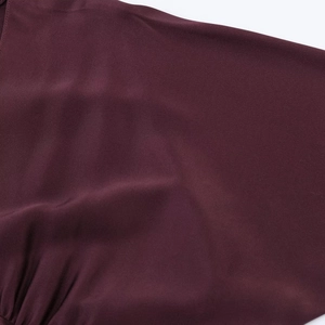 Macro shot of dark burgundy silk satin dress fabric with elegant pleated texture detail