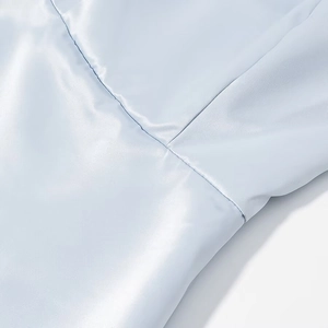 Macro detail of light blue satin fabric with precise cross-stitching on elegant dress