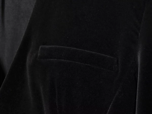 Detail of premium black velvet fabric showing a refined welt pocket and fine tailoring