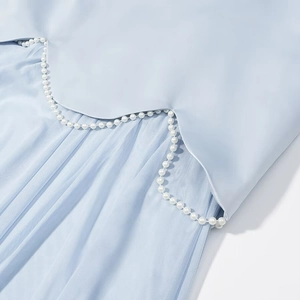 Close-up of light blue dress with scalloped edges and white faux pearl trim decoration