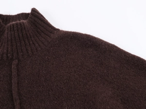 Close-up detail of dark brown knit dress showing thick wool texture and high collar