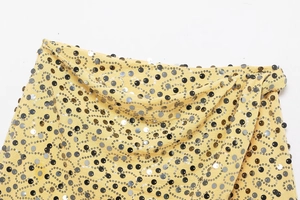 Macro detail of yellow sequin mini skirt featuring black and silver glitter wave patterns