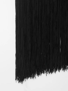 Détail du tissu à franges noires avec plusieurs couches et ourlet irrégulier de la robe
