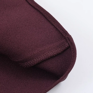 Macro shot of burgundy satin dress showing refined flat-felled seams and edge stitching detail