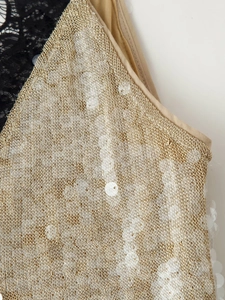 Detail of metallic woven fabric with white sequins and black floral lace patchwork