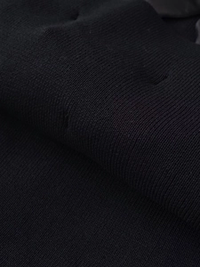 Gros plan sur un tissu tricoté noir montrant la texture détaillée et le tissage serré