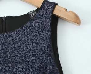 Detail of sequined fabric, interior brand label, and zipper on a navy blue sleeveless dress