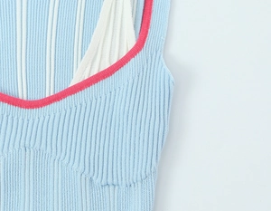 Détail du tricot côtelé bleu clair avec plis blancs et bordure rose contrastée sur le col