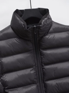 Détail du col montant et du zip sur le gilet matelassé noir de style streetwear d'hiver